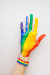 A woman's hand is smeared with paint and a bracelet in the colors of the LGBT rainbow. The concept of love, sexual tolerance, LGBT pride, same-sex relationships, homosexuality.