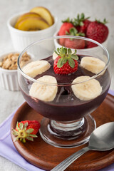 Brazilian typical acai bowl with fruits and muesli over wooden background