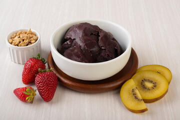 Brazilian typical acai bowl with fruits and muesli over wooden background