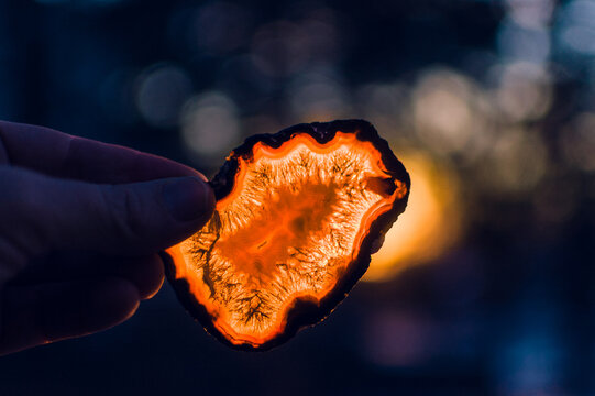 Slice Of Gold Agate Held In Front Of Setting Sun