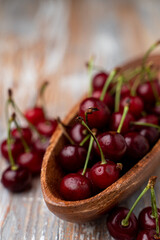 Heap of ripe cherries in a wooden bowl, selective focus on a wooden table for a magazine