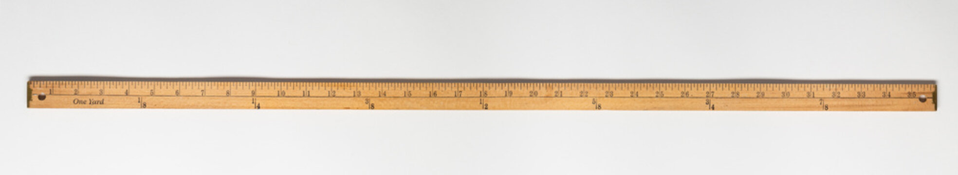 Wooden yardstick on white backgrounds whit inches and yard fractions scales.
