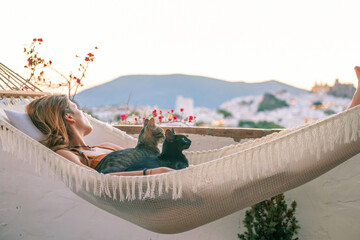 Young Hispanic woman lying in hammock with her cat