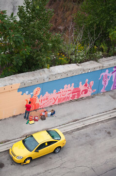 artist paints mural on a city street