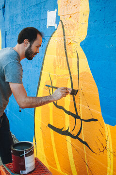 artist paints mural on a city street