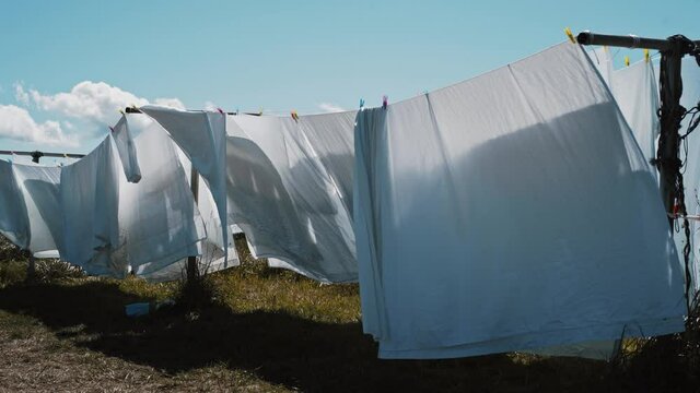 white bed sheets on a clothes line moving gently with the wind in a natural setting