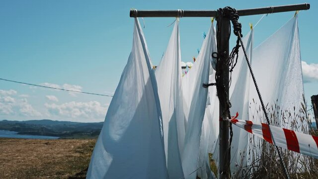 white bed sheets on a clothes line moving gently with the wind in a natural setting