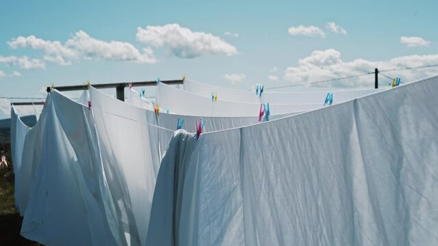 white bed sheets on a clothes line moving gently with the wind in a natural setting