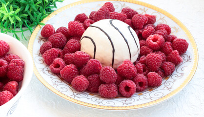 White plate with raspberries and sponge cake on a white background.