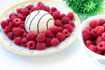 White plate with raspberries and sponge cake on a white background.