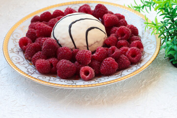 Raspberry berries on a plate with a cake on a white background with foliage.