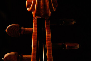 Close-up of violin fiddle pegbox pegs and scroll on dark moody red background