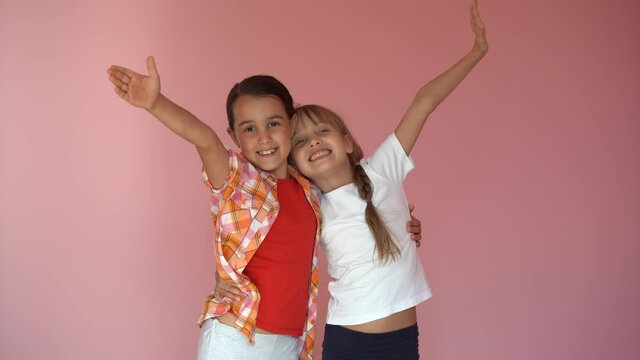 two little girls on a pink background. Friends. Excited young children