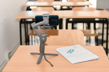 Phone gimbal stabilizer with a phone on a desk in an empty classroom, new normal back to school during Covid-19