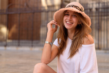 Young female with a cute white top and jeans sitting on the stairs and enjoying the nice weather