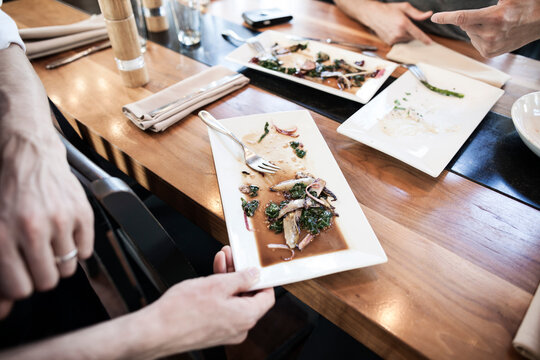 Waiter Clearing Dirty Dishes From A Table