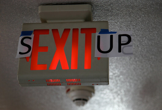 Exit sign with some added letters to spell Sex It Up in a college dorm hallway