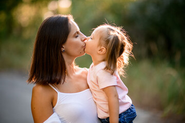 Close-up of woman with little girl in her arms who are kissing each other.