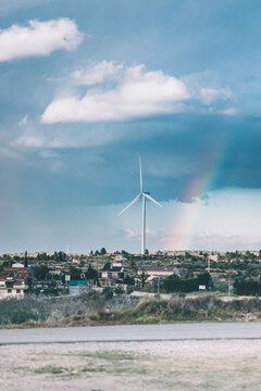 Conceptual picture of an electric windmills on a windy day with rainbow at background.