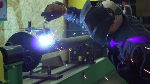 Cardan repair. A welder wearing a protective mask and gloves is welding the cardan elements.