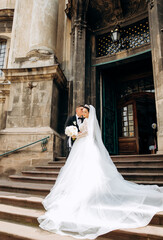 Loving couple standing on the stairs at the entrance to the church in the Baroque style