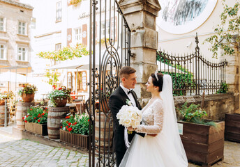 Charming young couple standing near a wrought iron gate on the street town