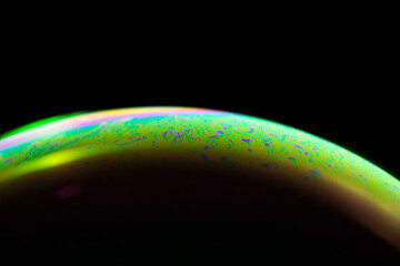 Detail of light in a soap bubble, allusion to the micro universe in a studio with a black background, use of natural and artificial light.