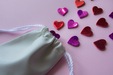 small white leather bag and pink background with hearts top view. St. Valentines Day. greeting card