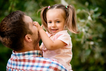 Close-up of little cute girl smiling in the arms of her father.