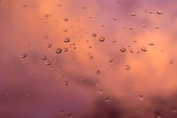 Raindrops on window. Cloudy sky in evening light outside the window. Abstract blurred image.