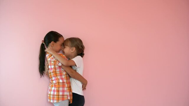 two little girls are angry and laugh on a pink background