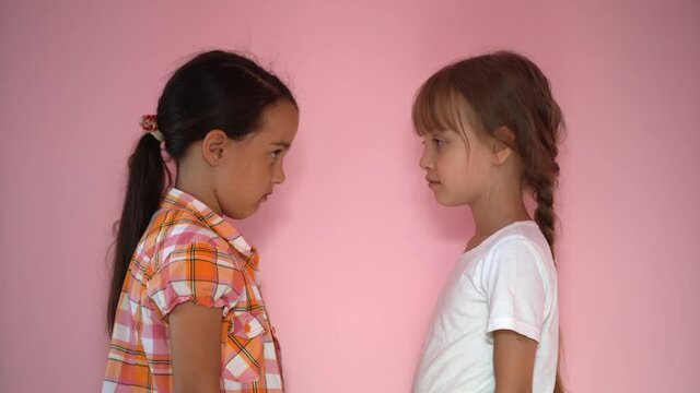 two little girls are angry and laugh on a pink background