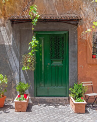 Fototapeta na wymiar vintage house facade with green door and flowerpots, Trastevere old neighborhood, Rome Italy