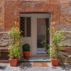 vintage house facade with white door and flowerpots, Trastevere old neighborhood, Rome Italy