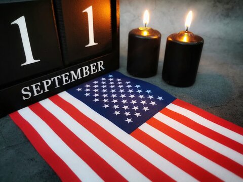 September 11th. Patriot Day and Memorial concept.
Two burning candles with United States of America flag on dark background. Copy space. 
