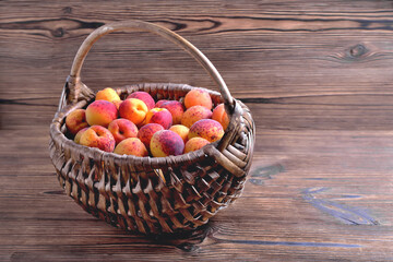 Natural ripe apricots in a wicker basket on a natural wooden background, copy space