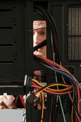 Young man repairs a computer system unit, changes parts, video card and hard drive, sets new...