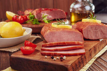 Pieces of smoked pork loin with rosemary branch, lemon and spices on the wood cutting board