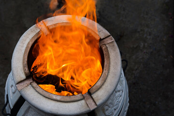 Firewood is being burned in tandoor heating it before roasting barbeque at night. Tandoor is a special spherical or pitcher-shaped grill for cooking a variety of food among the peoples of Asia.