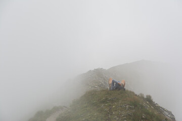 Obraz premium Tired hiker lies on a mountain ridge in a thick fog