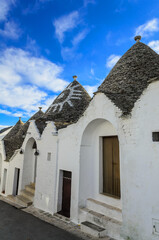 Fototapeta na wymiar Conical roofs of trulli in Alberobello.. Each trullo is decorated with pinnacle and symbol . Symbols are divided into 3 categories primitive, christian and magical.