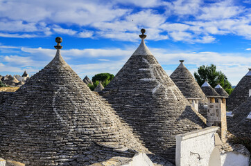 Fototapeta na wymiar Conical roofs of trulli in Alberobello.. Each trullo is decorated with pinnacle and symbol . Symbols are divided into 3 categories primitive, christian and magical.
