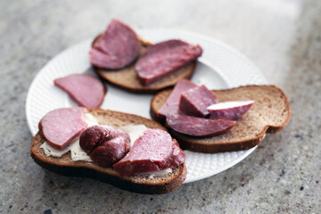 Sandwiches with butter and sausage on a white plate
