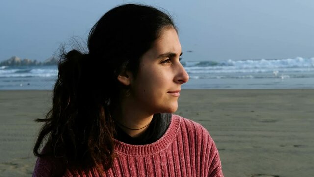portrait of the profile of a girl at the beach looking at the sun. calm thoughtful latin brunette teenager.