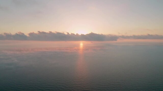Aerial video over а morning calm sea and beautiful sunrise with low clouds
