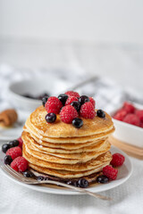 Homemade pancakes with raspberries and blueberries on white plate.
