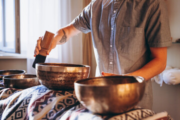 Nepal Buddha copper singing bowl at spa salon. Young bearded man doing massage therapy singing bowls in the Spa. Sound therapy, recreation, meditation, healthy concept