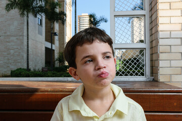 7 year old Brazilian child, on a sunny afternoon, chewing the chocolate with his mouth closed and...
