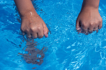 Hands clenched into fists over the blue water. Close up
