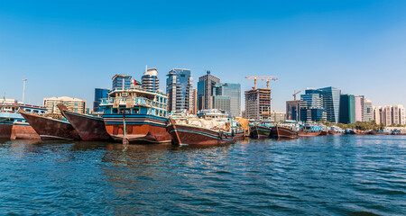 Fototapeta premium Dhow boats and modern skyscrapers on the Dubai Creek in the UAE in springtime